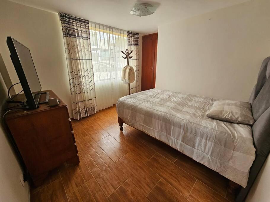 una camera da letto con un letto e una TV su un pavimento in legno di Casa familiar en Arequipa ad Arequipa