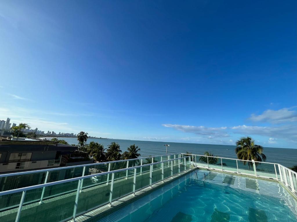 una piscina con el océano en el fondo en Flat Beira mar de João Pessoa no Bairro Cabo Branco, en João Pessoa