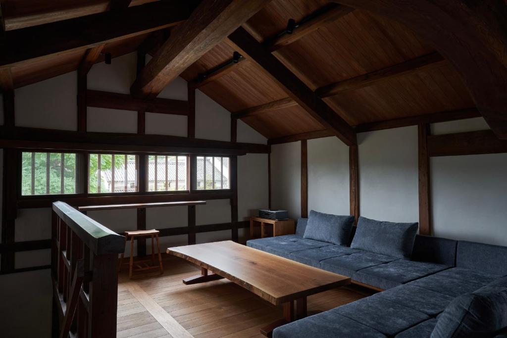 仓敷滔々 日本郷土玩具館 蔵の宿 toutou, Gangukan Kura no Yado的客厅里有一张蓝色的沙发和一张桌子