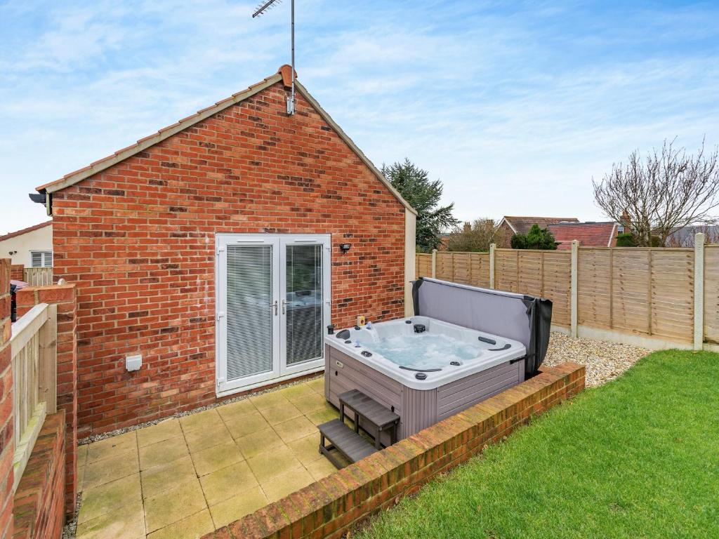 a hot tub in the backyard of a brick house at The Nest in Bempton
