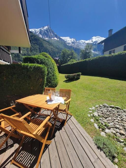 une table et des chaises en bois sur une terrasse avec une montagne dans l'établissement Chamonix Garden Flat with a View of Mont-Blanc - Référence XEPKMM, à Chamonix-Mont-Blanc