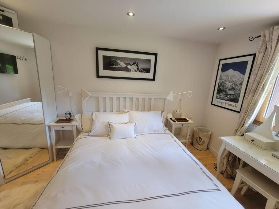 een slaapkamer met een groot wit bed en een bureau bij Chamonix Garden Flat with a View of Mont-Blanc in Chamonix-Mont-Blanc