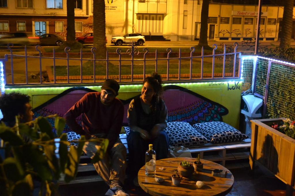 un grupo de personas sentadas en un porche con una mesa en Nómada Eco-Hostal, en Valparaíso