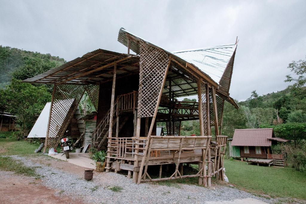 un edificio de madera con techo y porche en Khaokhopimphupha farmstay เขาค้อพิมภูผาฟาร์มสเตย์ ไม่มีไฟฟ้า น้ำจากน้ำตกธรรมชาติ Low cabon with Sustainability cares, en Ban Non Na Yao
