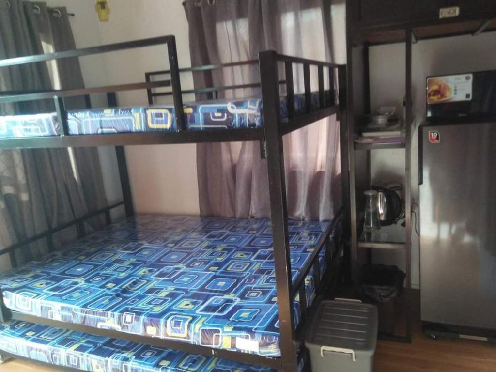 Kua's Pad Batangas Room في ليان: سريرين بطابقين في غرفة مع ثلاجة