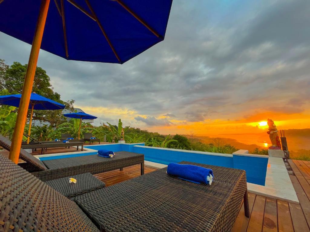 een patio met tafels en parasols en de zonsondergang bij D'Lesung Villas Lembongan in Nusa Lembongan