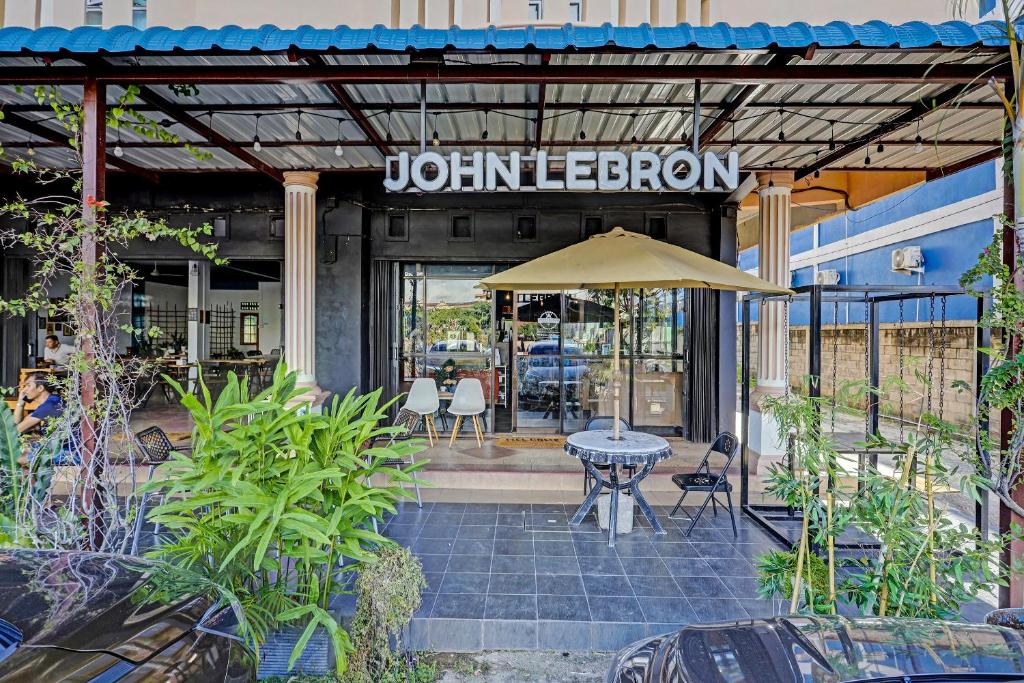 un patio con una mesa y una sombrilla frente a un restaurante en Collection O 91499 John Lebron House, en Sagulung