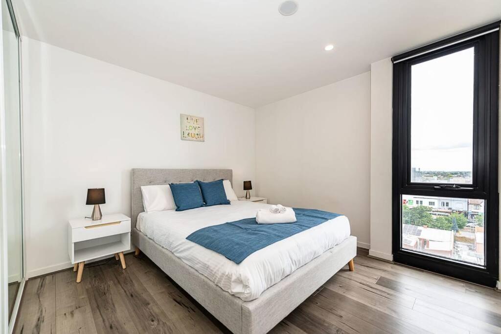 Un dormitorio blanco con una cama grande y una ventana en Cozy Box Hill Apartment, en Box Hill