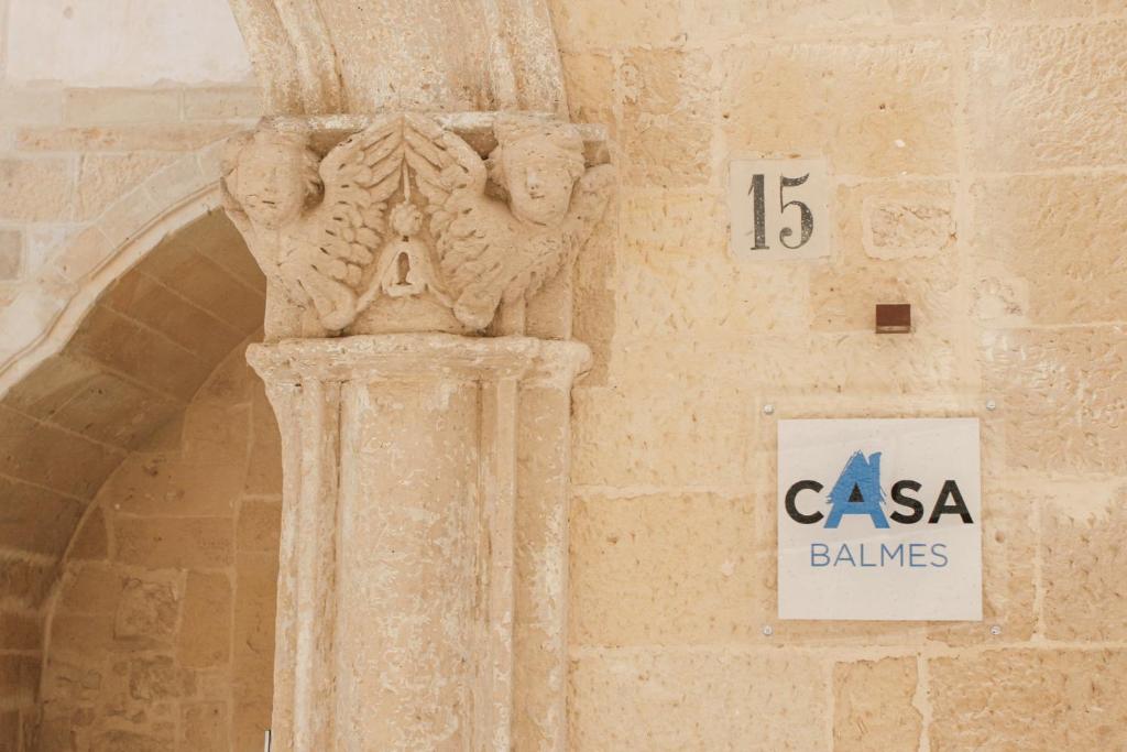 una columna de piedra en el lateral de un edificio con una señal en Casa Balmes, en Lecce