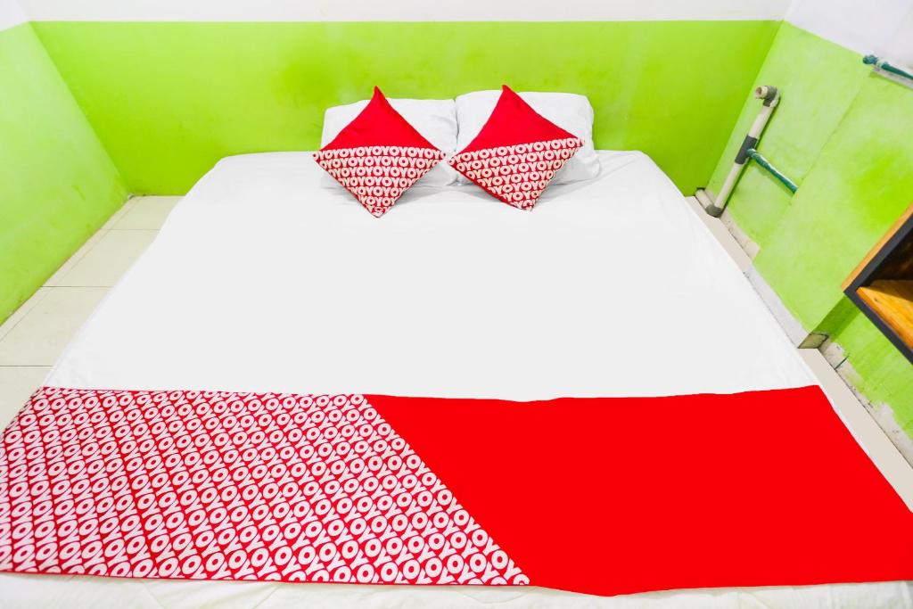 Una cama con dos almohadas rojas y blancas. en OYO 91344 Wr House Syariah Batam en Jodoh