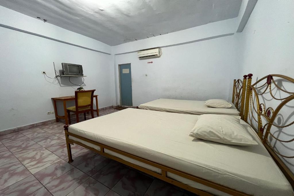 two twin beds in a room with a tv at OYO 91757 Surya Hotel in Watansopeng