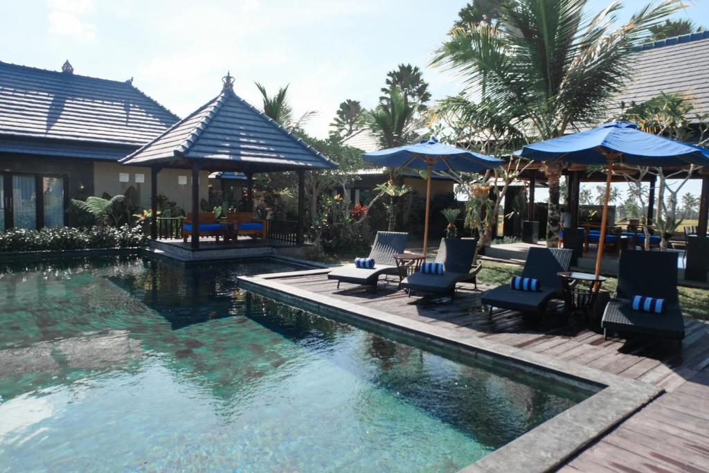 een zwembad met stoelen en parasols in een resort bij Villa Cendrawasih Ubud in Tegalalang