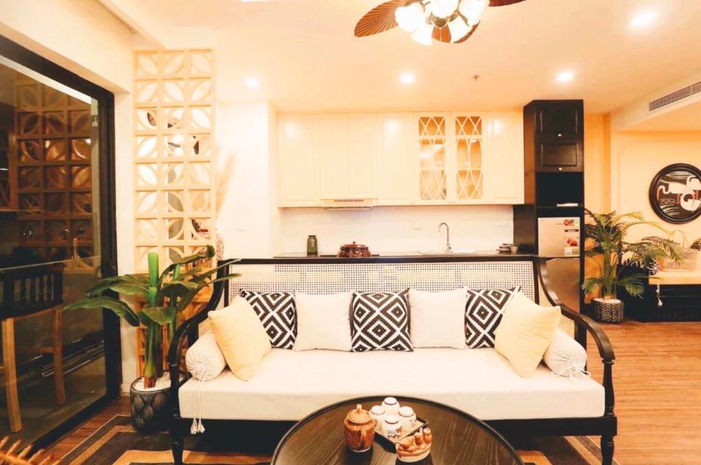 a living room with a white couch and a kitchen at FLC Luxury Apartment Quy Nhon in Quy Nhon
