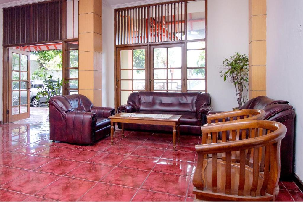 a living room with leather furniture and a coffee table at Super OYO 759 Hotel Dewi Sri in Timuran