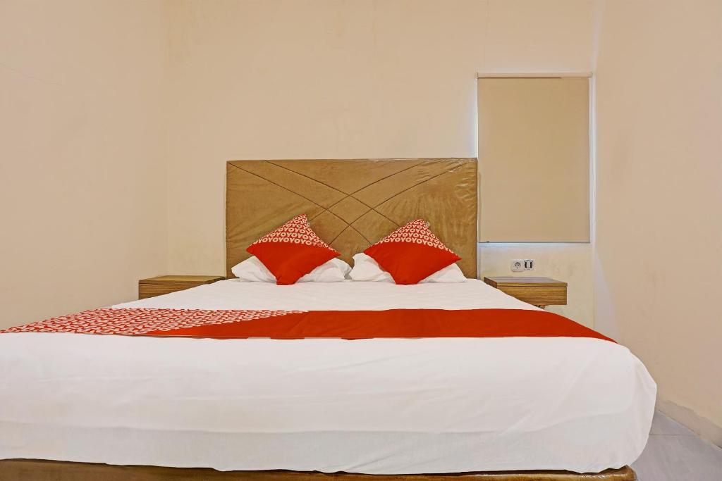 1 dormitorio con 1 cama grande con almohadas rojas y blancas en Collection O 91414 Hotel Marina Beach en Makassar