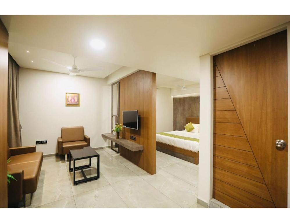 Hotel R City Inn By Mantram Hospitality في راجكوت: غرفه فندقيه بسرير ومكتب وكرسي
