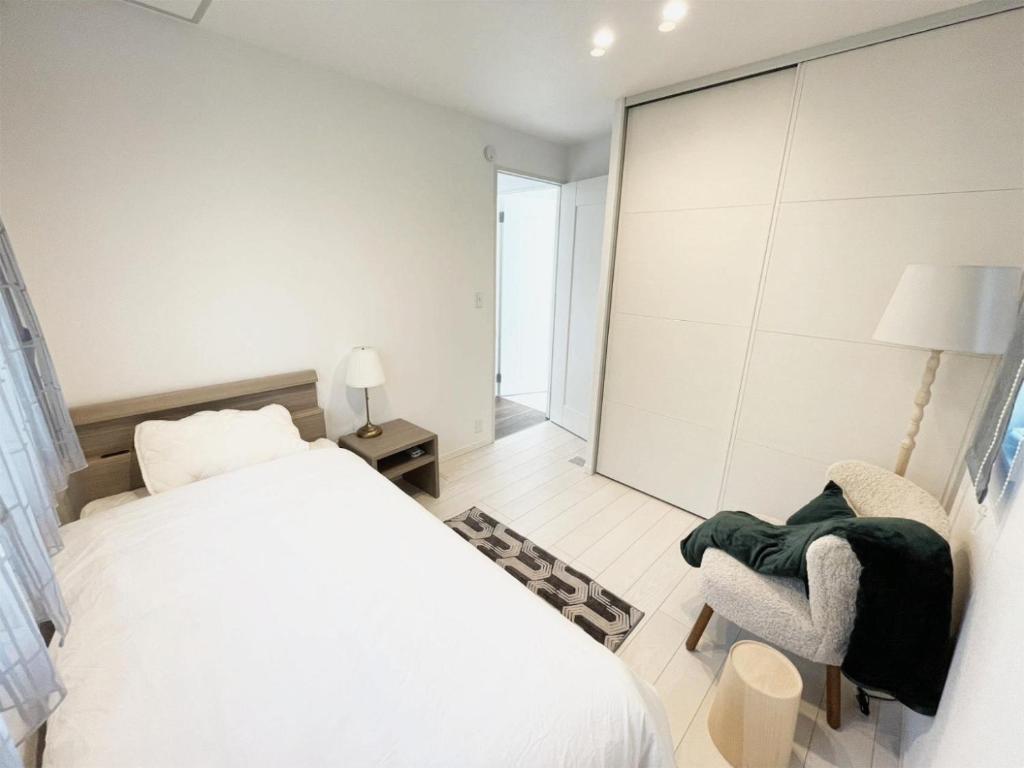 1 dormitorio blanco con 1 cama y 1 silla en 熊本民宿-悠然别苑, en Ozu