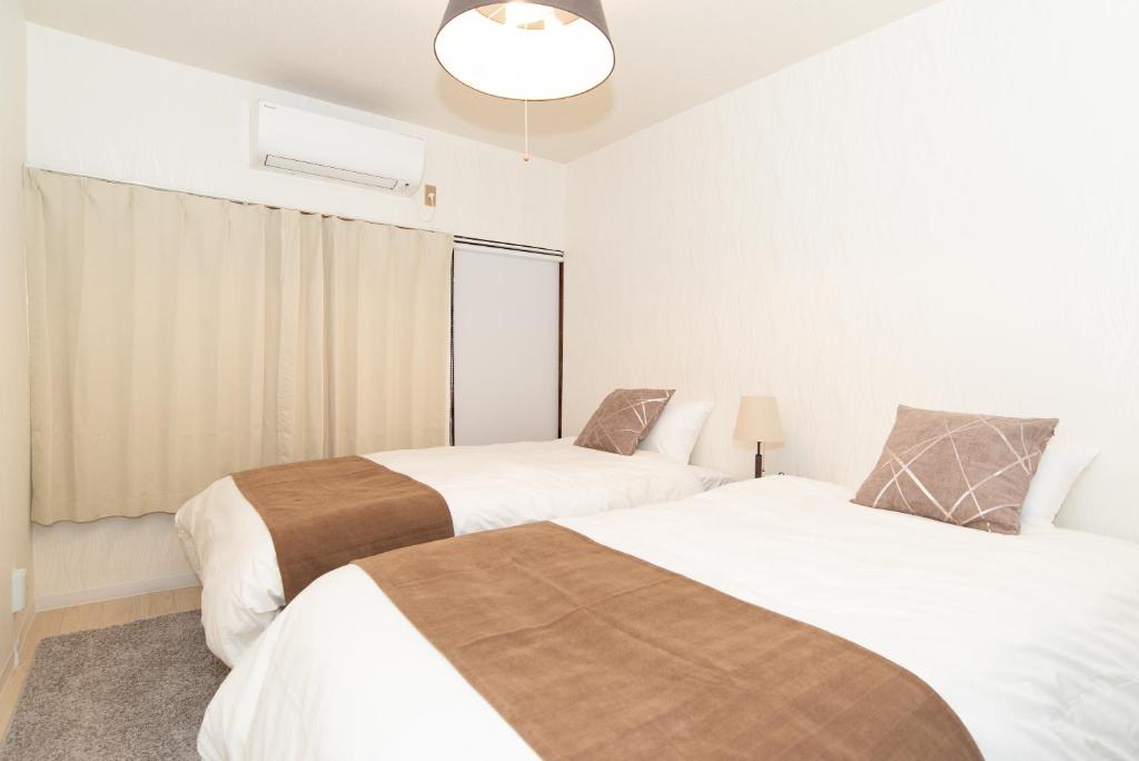 a bedroom with two beds and a window at リノディア京橋 in Osaka