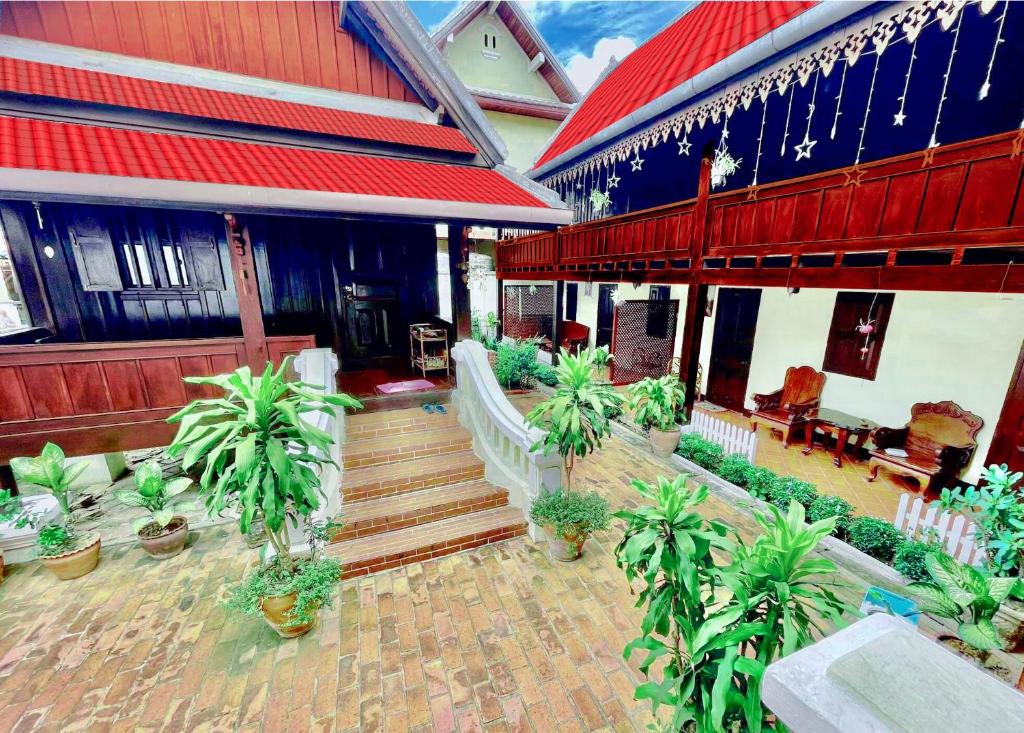 ein Haus mit Topfpflanzen vor einem Gebäude in der Unterkunft Villa Phathana Royal View Hotel in Luang Prabang