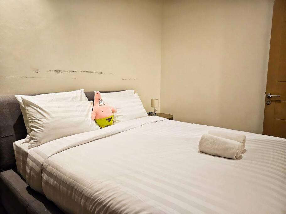 a large white bed with a stuffed pig on it at Aksara de jivva at Pakuwon indah Cluster in Surabaya