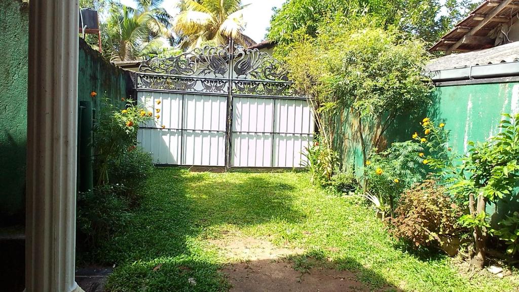 a garden with a gate and a yard with grass at VA Villa Hikkaduwa in Hikkaduwa