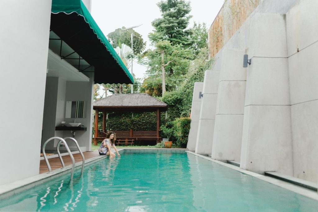 uma menina sentada na piscina de um hotel em Villa Majesty Dago em Bandung