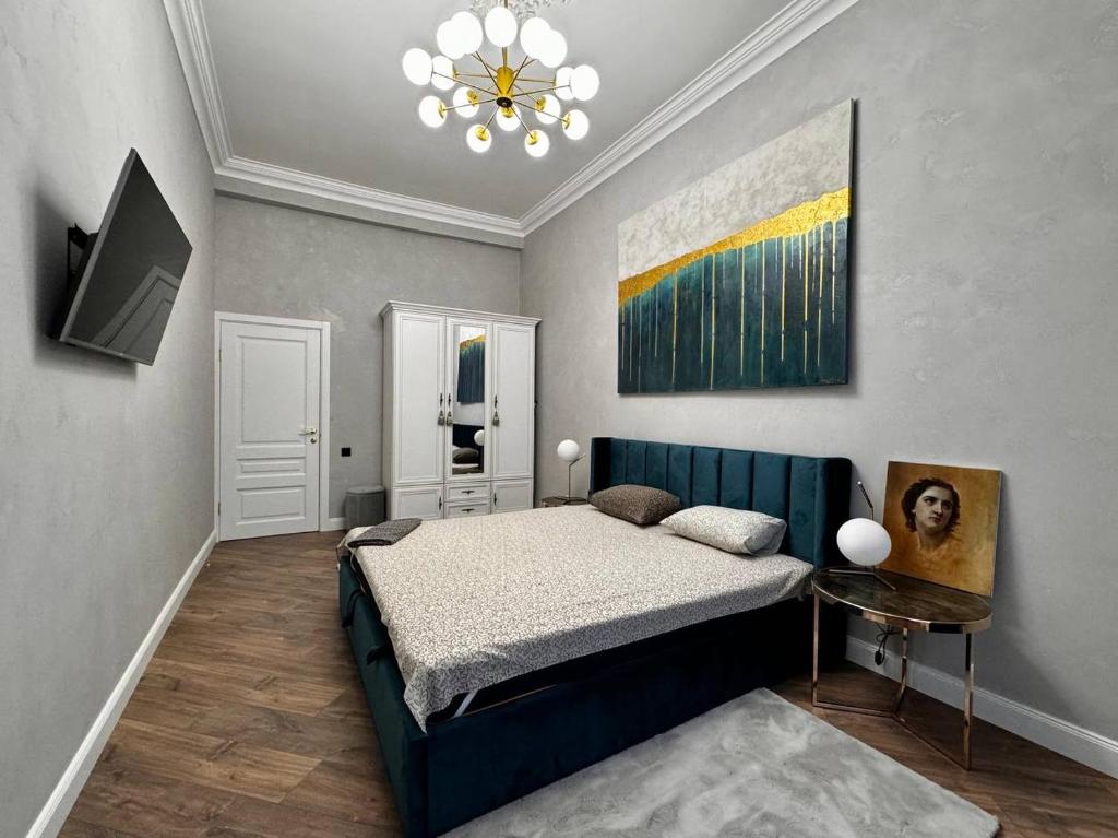 a bedroom with a bed and a painting on the wall at Deribasivska 10 Luxury Apartment in Odesa