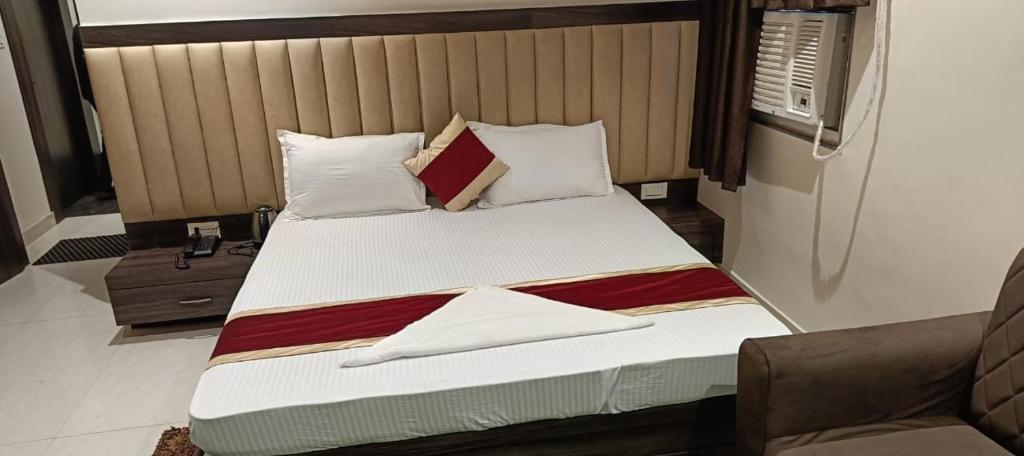 een slaapkamer met een bed met witte lakens en kussens bij hotel bodhi inn in Gaya