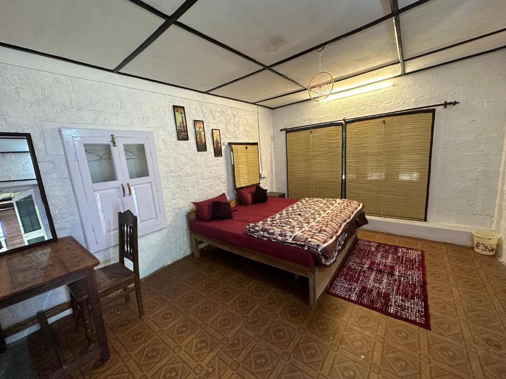 1 dormitorio con cama, mesa y escritorio en Dreamwoods A travellers farmhouse, en Dharamshala