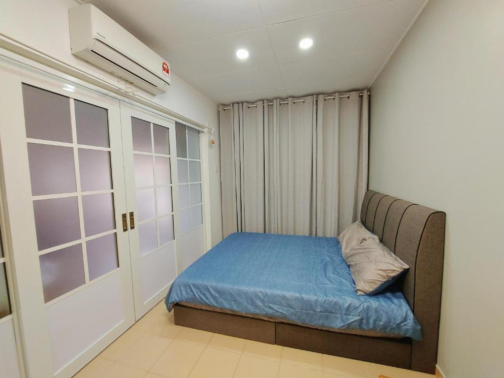 um pequeno quarto com uma cama azul e uma janela em Coz26 Bercham House Spacious Family Suite 14pax 3Parking em Ipoh