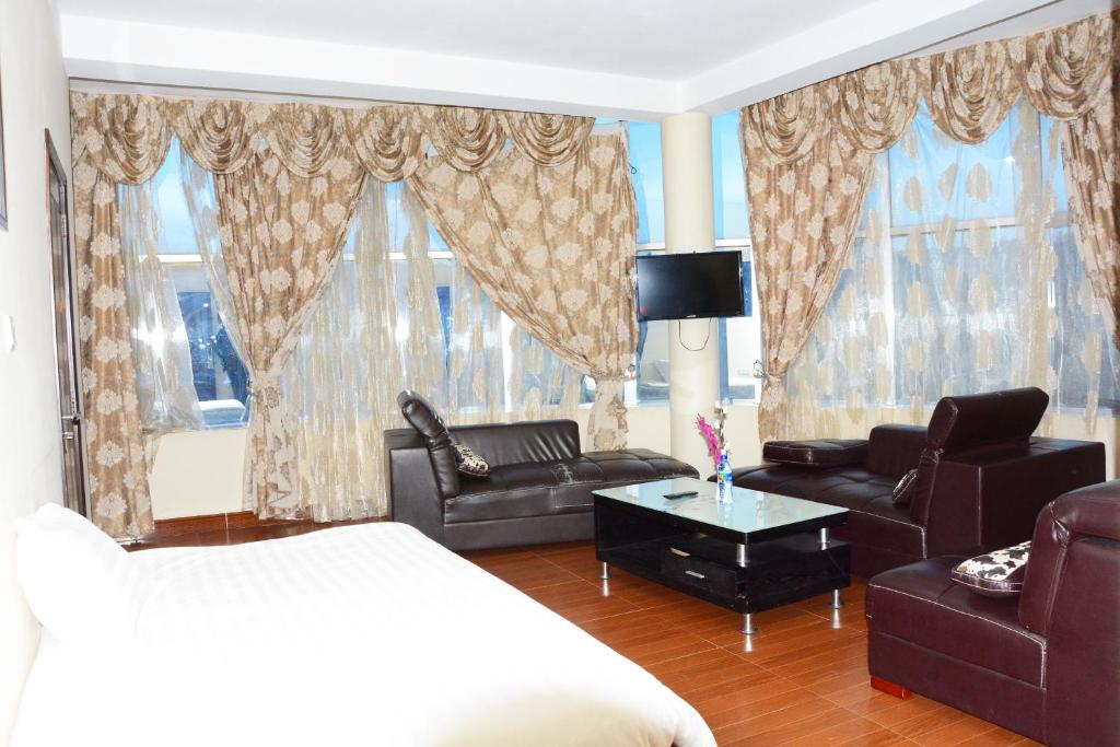 ein Schlafzimmer mit einem Bett, einem Sofa und Stühlen in der Unterkunft Yaredzema International Hotel in Aksum