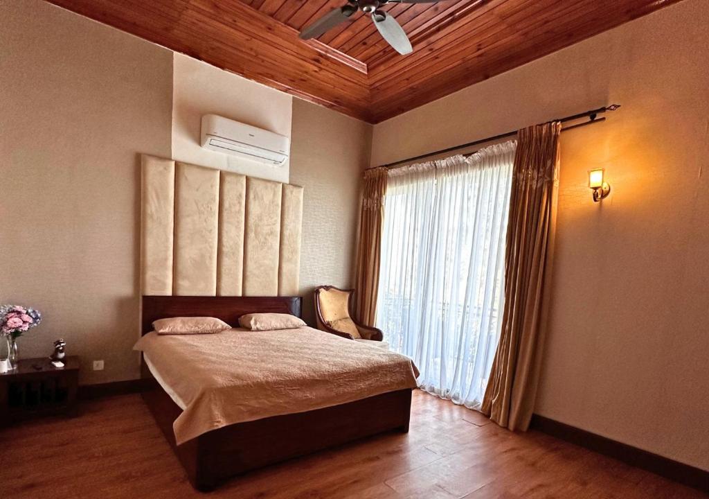 a bedroom with a bed with a ceiling fan and a window at PINETOP RESORT in Khānpur