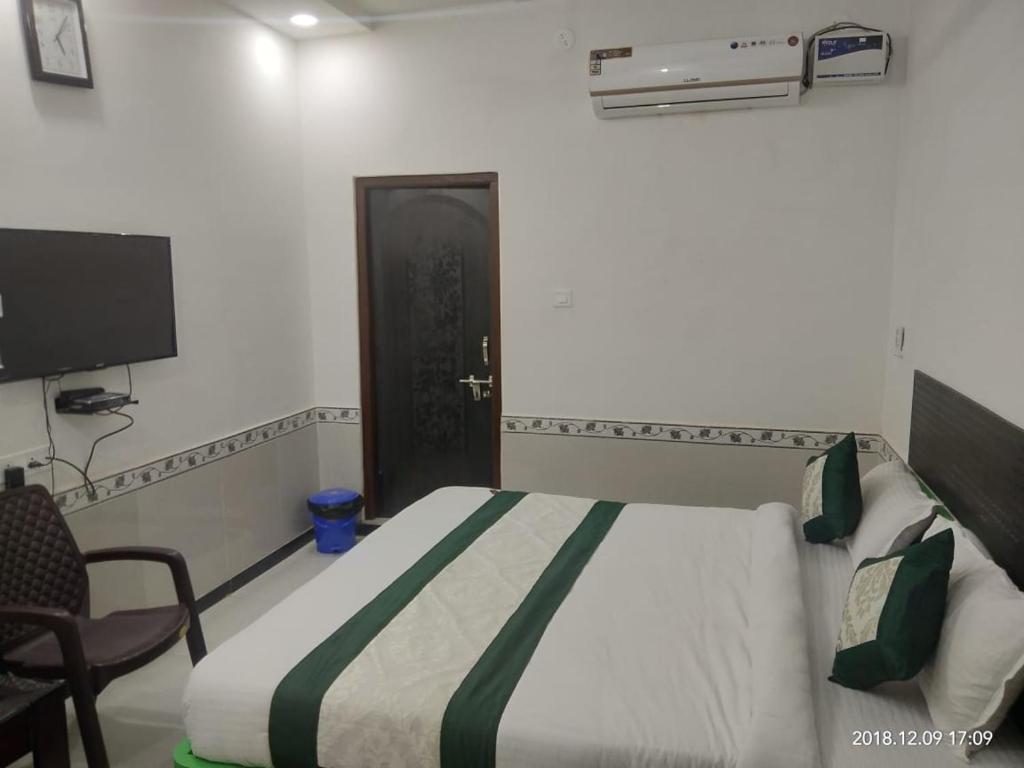 um quarto com uma cama, uma porta e uma cadeira em Hotel RJ 15 jaisalmer em Jaisalmer