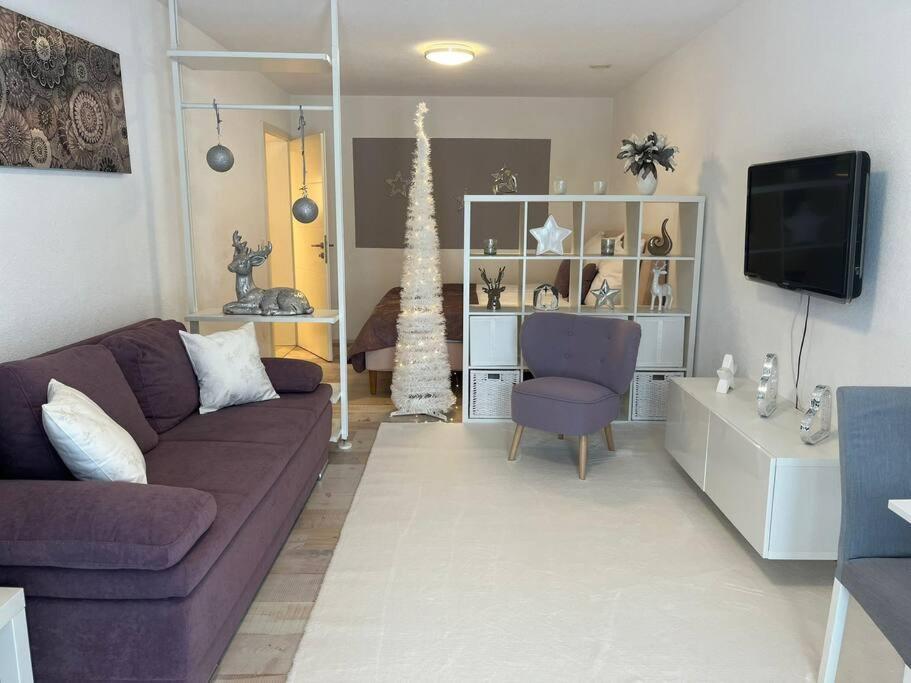 sala de estar con sofá púrpura y TV en Sonnenblick, en Teufenbach