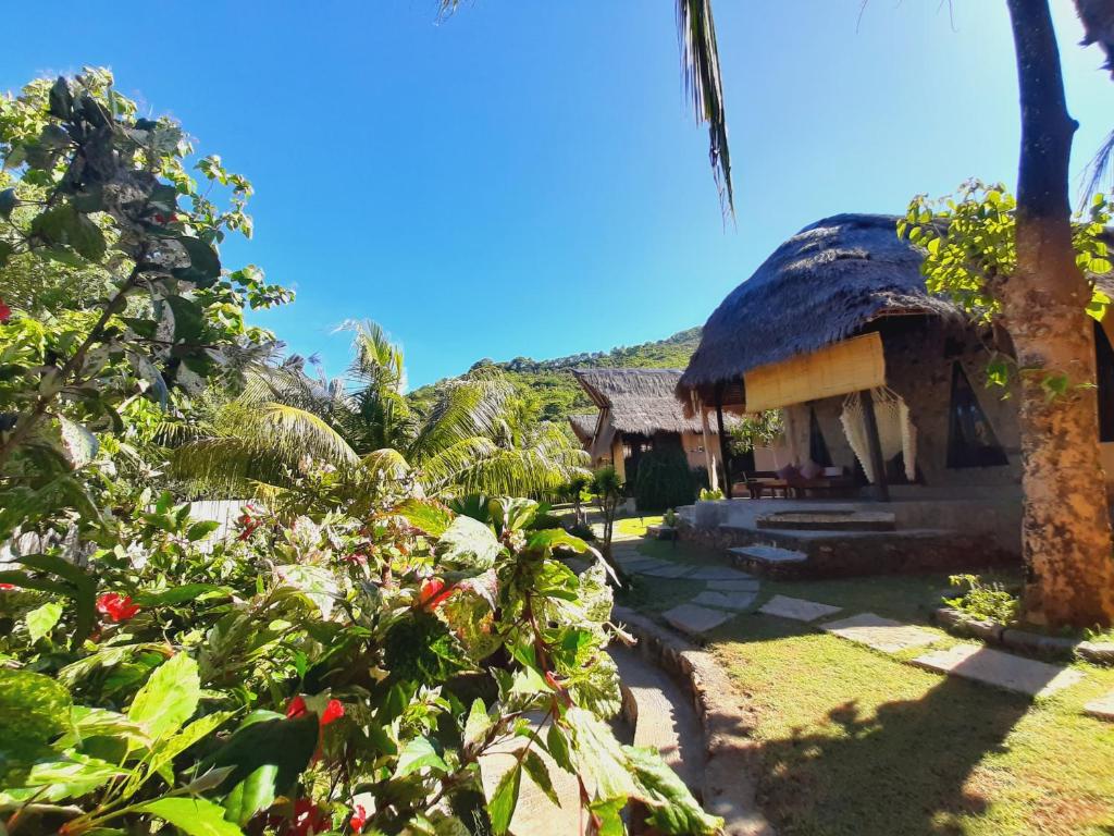 una casa con techo de paja y algunas plantas en JEJU Cottages, en Kuta Lombok
