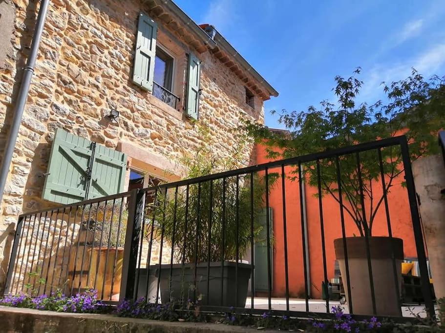 une clôture noire devant un bâtiment en briques dans l'établissement Agréable maison de village avec piscine, à Saint-Hilaire-de-Brethmas