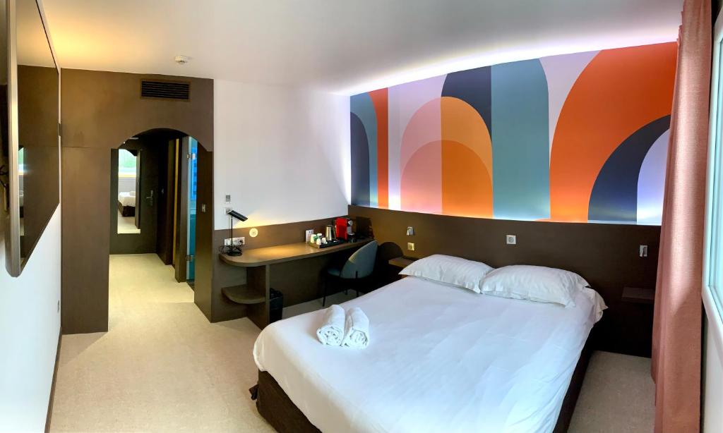 Dormitorio con cama, escritorio y pared colorida en B&B HOTEL Saint-Avold Nord, en Saint-Avold