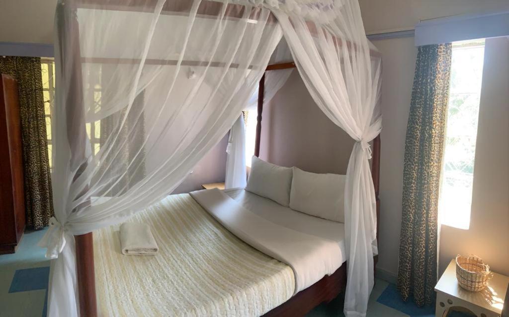 um quarto com uma cama de dossel e cortinas brancas em TAPHE GUEST RESORT em Naivasha