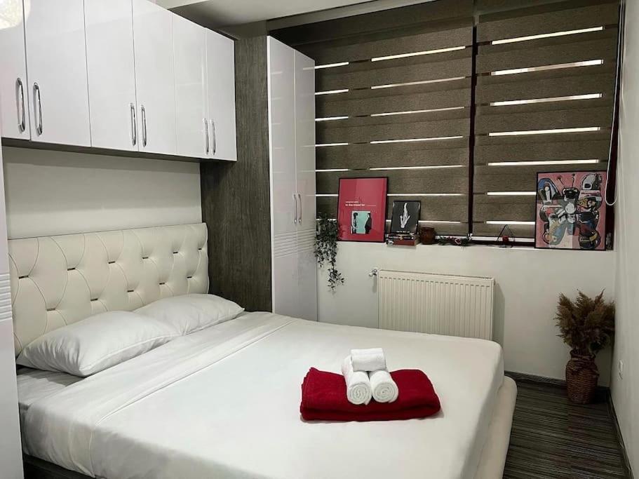 a white bed with two towels on a red blanket at Pejton's Hidden Gem: 94squares in City Center in Pristina