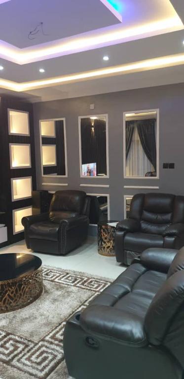a living room with black leather furniture and a tv at Gradun in Ikeja