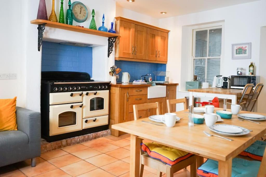 a kitchen with a wooden table and a stove top oven at Heart of Totnes, Period Property in Dean