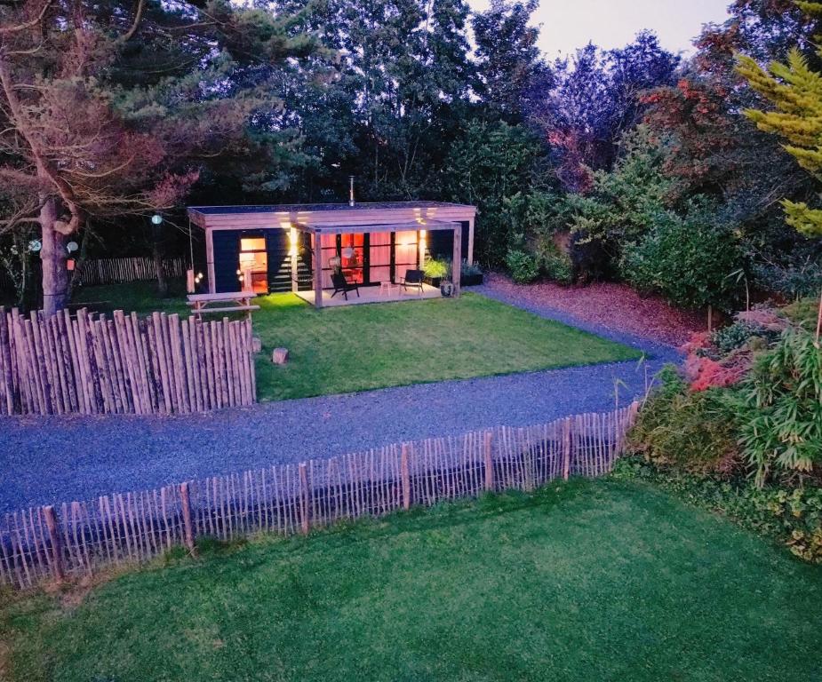 een klein huis in een tuin met een hek bij Hoogtij°d in Oostvoorne