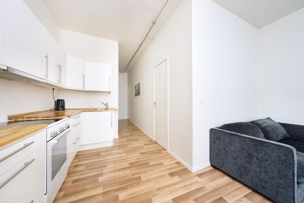 uma cozinha com armários brancos e um sofá preto em Grünerløkka Deluxe Apartments em Oslo