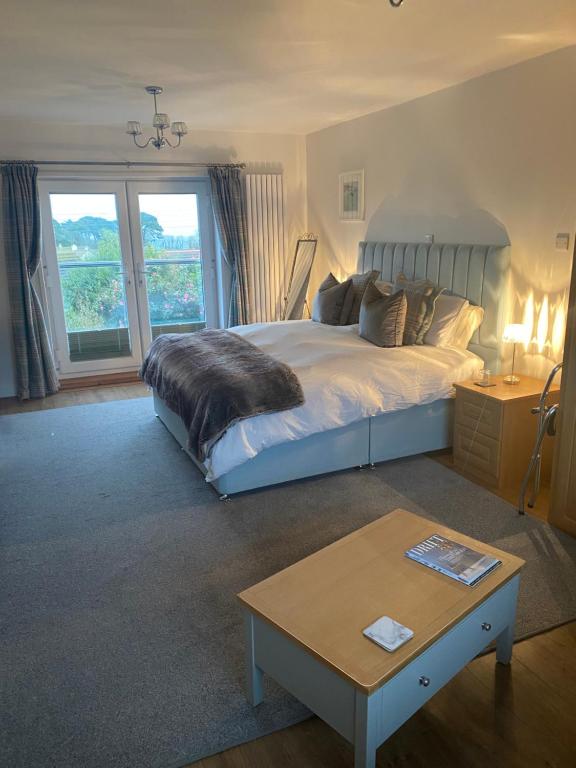 a bedroom with a large bed and a table at Downsfield Bed and Breakfast in St Ives