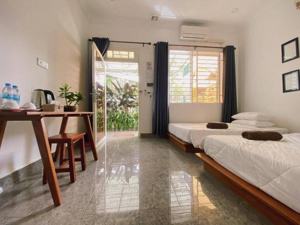 a bedroom with two beds and a desk and a table at Flower Home ផ្ទះសំណាក់ ហូមផ្កា in Sihanoukville