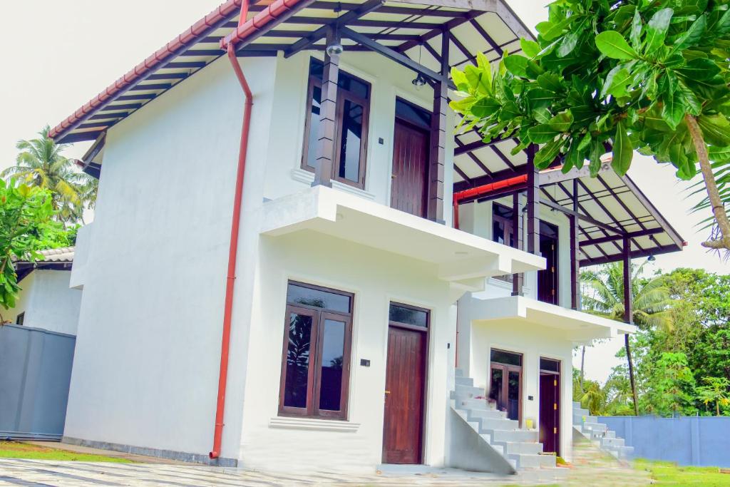 a white house with red doors and windows at Muthu Villa 94 Midigama in Ahangama East