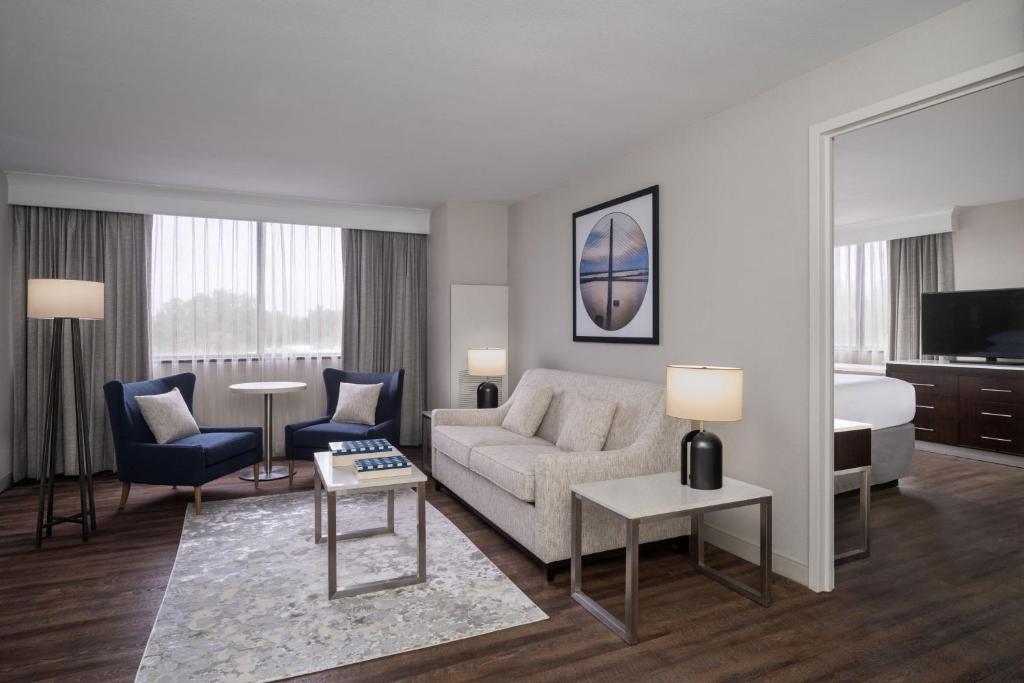 ein Wohnzimmer mit Sofa und ein Schlafzimmer in der Unterkunft Delta Hotels by Marriott Jacksonville Deerwood in Jacksonville