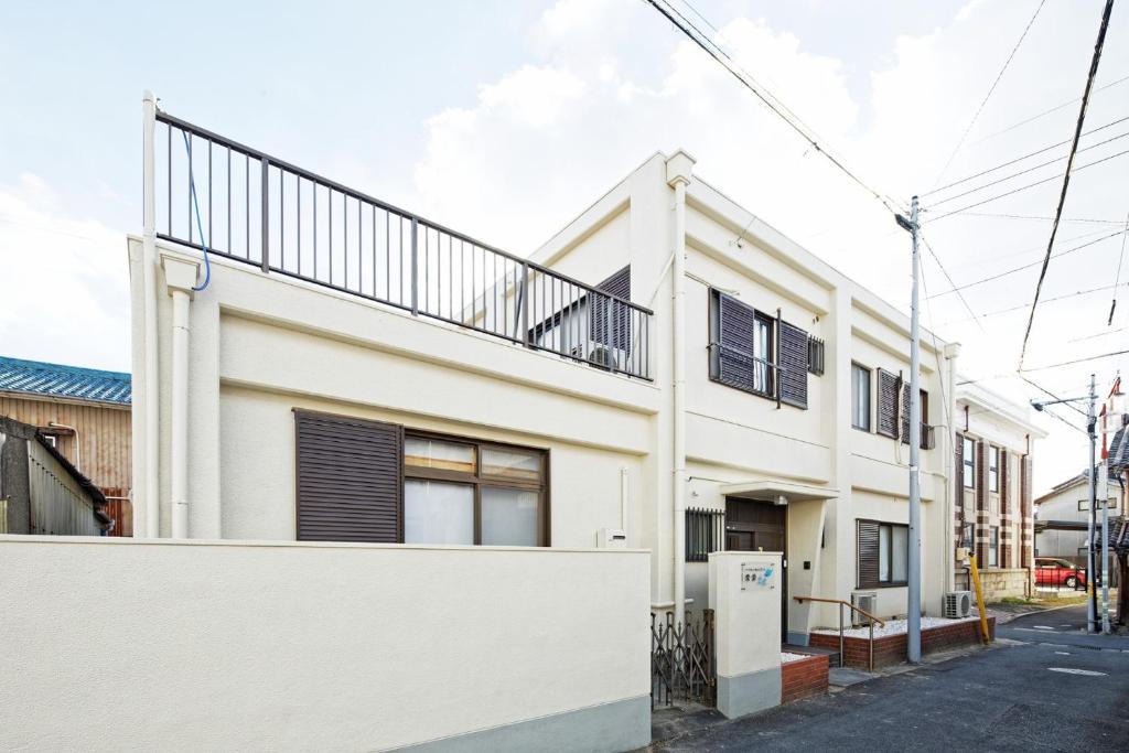 ein weißes Haus mit Balkon auf einer Straße in der Unterkunft BBQ & Residence Tokoname - Vacation STAY 86709v in Tokoname