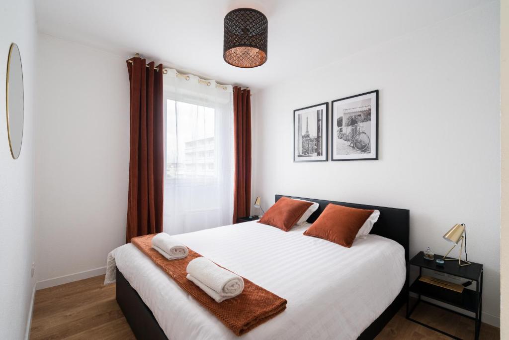 une chambre avec un grand lit blanc avec des oreillers orange dans l'établissement casa Lyon Appartement lumineaux, à Lyon