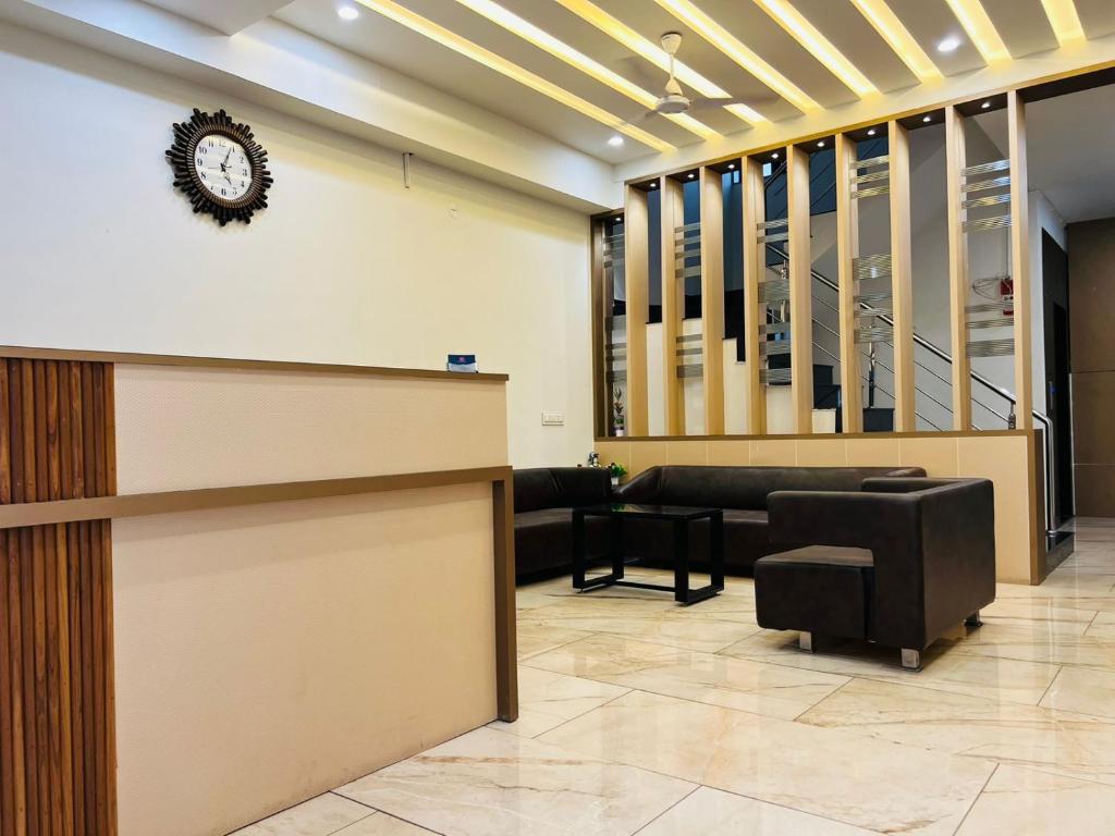 a lobby with a reception desk and a clock on the wall at Hotel Venus By Mantram Hospitality in Rajkot